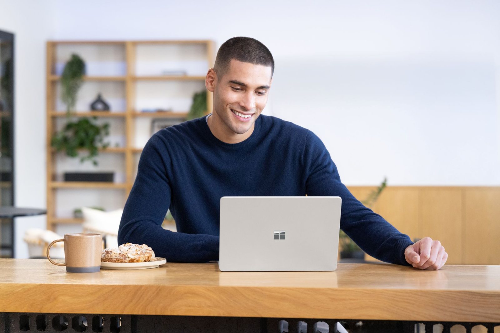 Nguoi dung ngoi quan ca phe lam viec tren laptop Windows 11 ben canh may ban